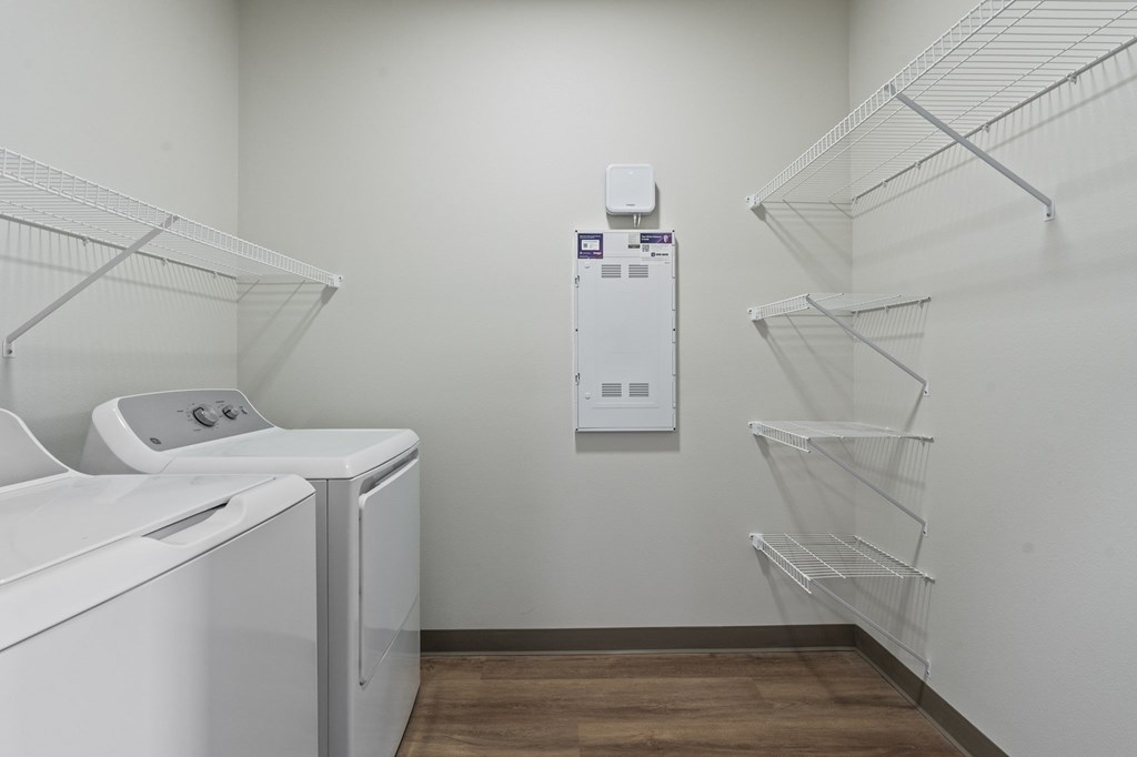 A laundry room with a washer and dryer and a wall-mounted dispenser.