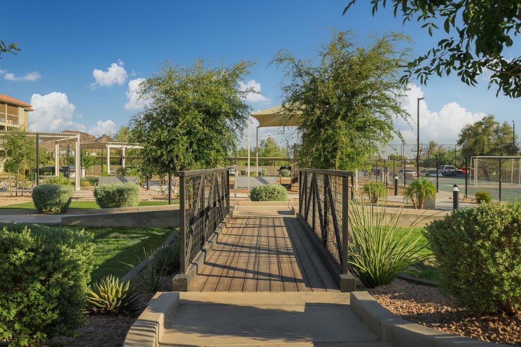 a bridge in a park with trees and a fence
