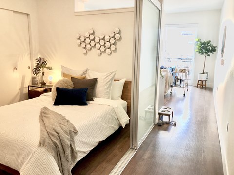 A bedroom with a large bed and a view of a balcony with two people on it.