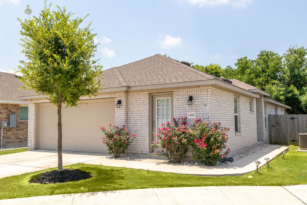 a white brick house with a tree in the front yard