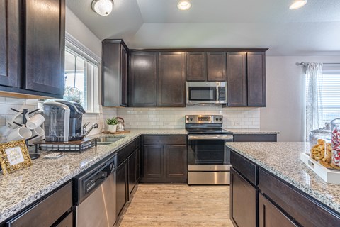 a kitchen with dark wood cabinets and granite counter tops