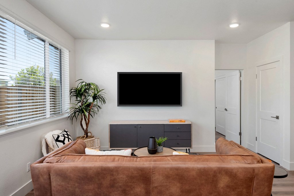 a living room with a brown couch and a tv on the wall
