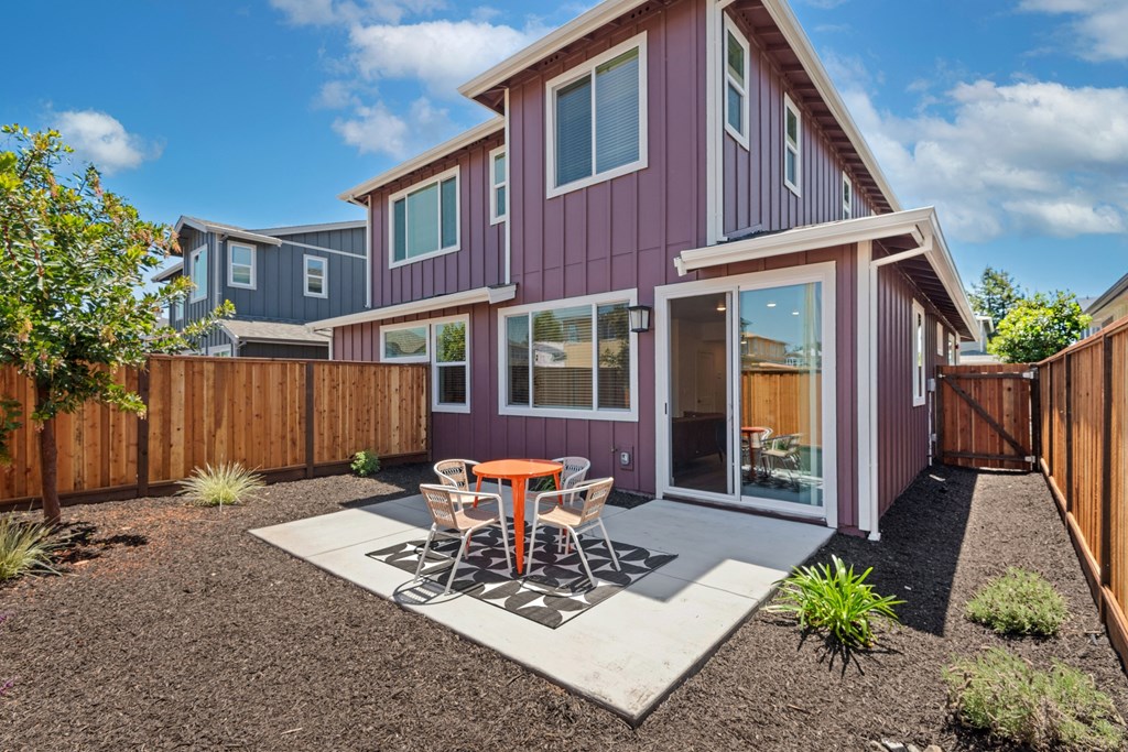a patio with a table and chairs in front of a house