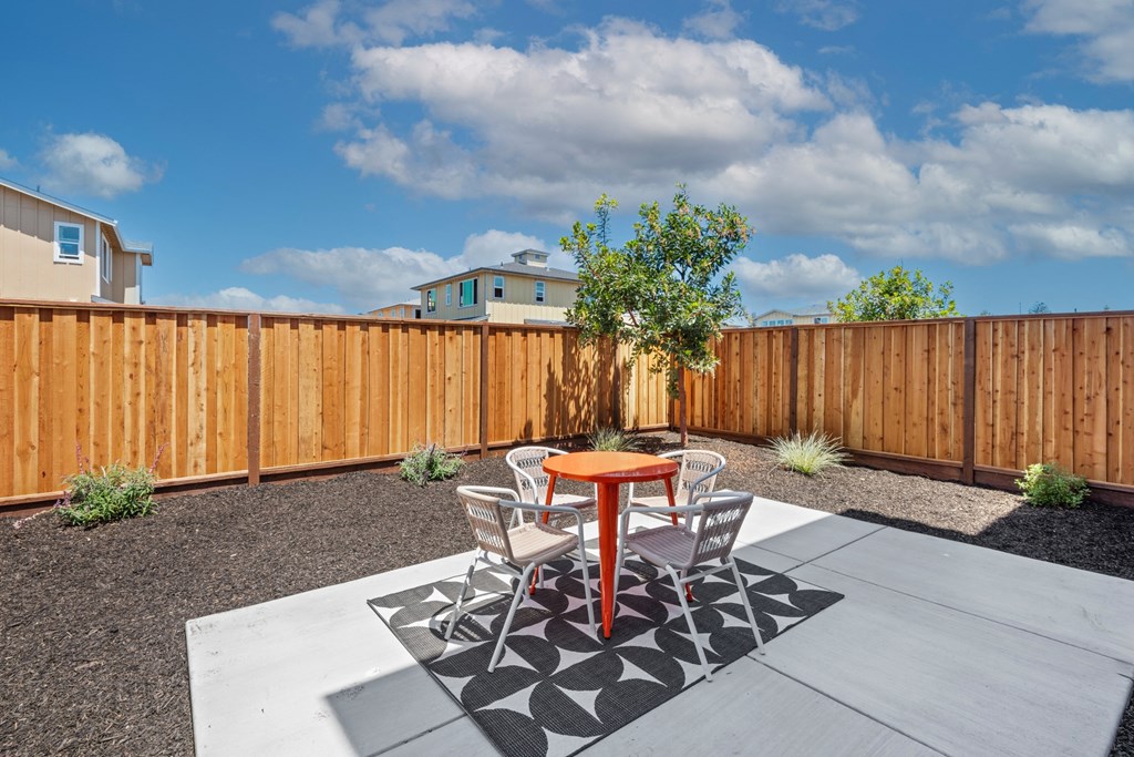 a patio with a table and chairs in front of a wooden fence