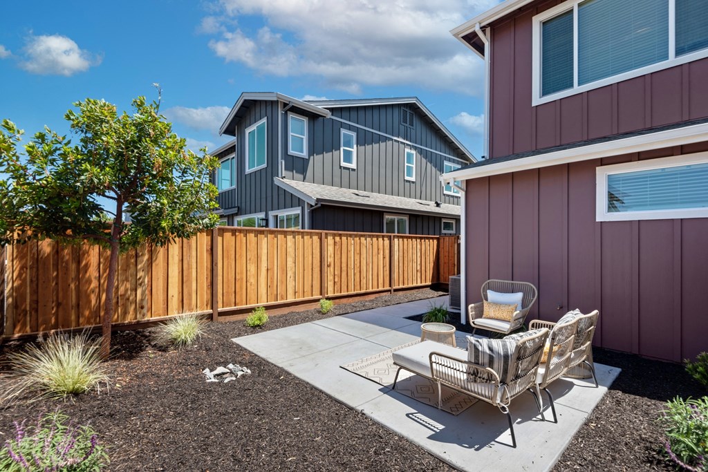 a patio with two chairs and a table in front of a house