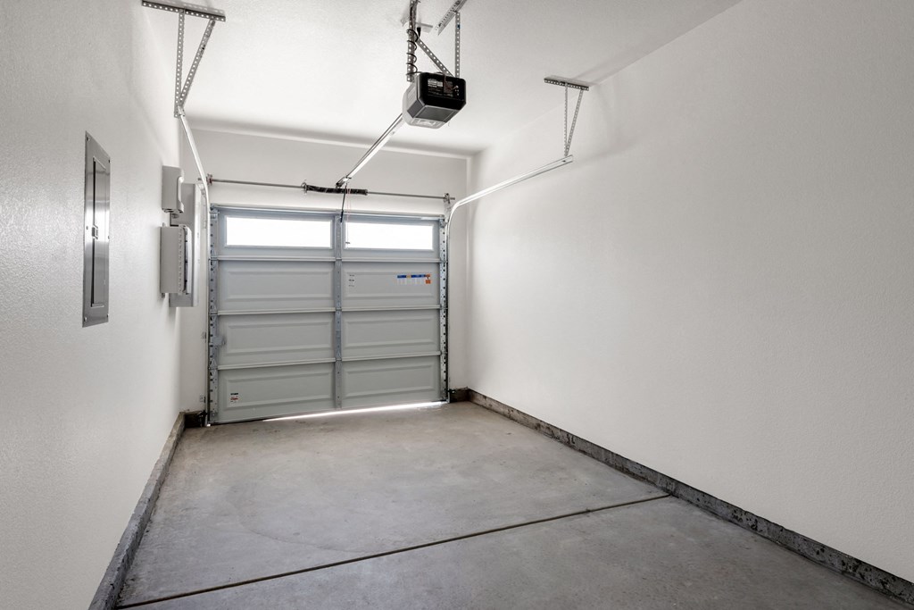 a garage door is in the corner of a white room with a concrete floor