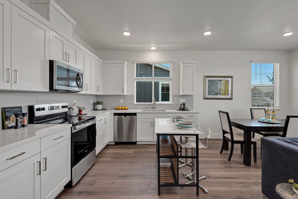 a kitchen and dining area with white cabinets and stainless steel appliances