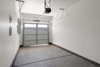 A white garage with a closed door and a hanging light fixture.