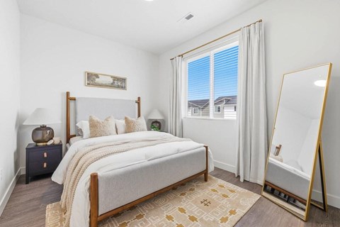 A bedroom with a large bed and a view of the outside through the window.