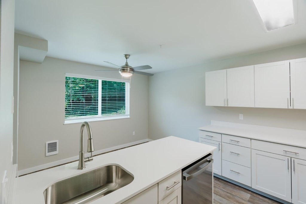 A kitchen with white cabinets and a stainless steel sink.