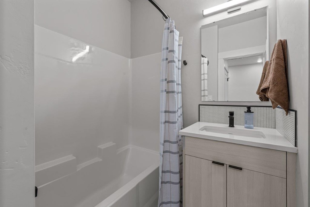 A white bathroom with a striped shower curtain.