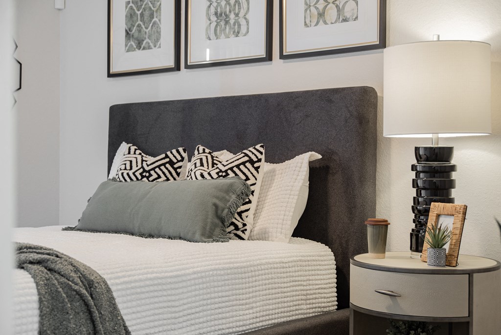 a bedroom with a bed with pillows and pictures on the wall