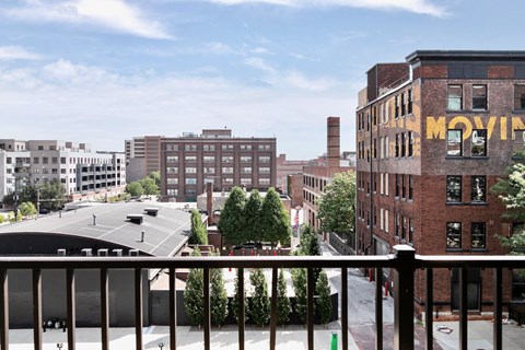 A view of a city from a balcony with a building that says "MOVING" on it.