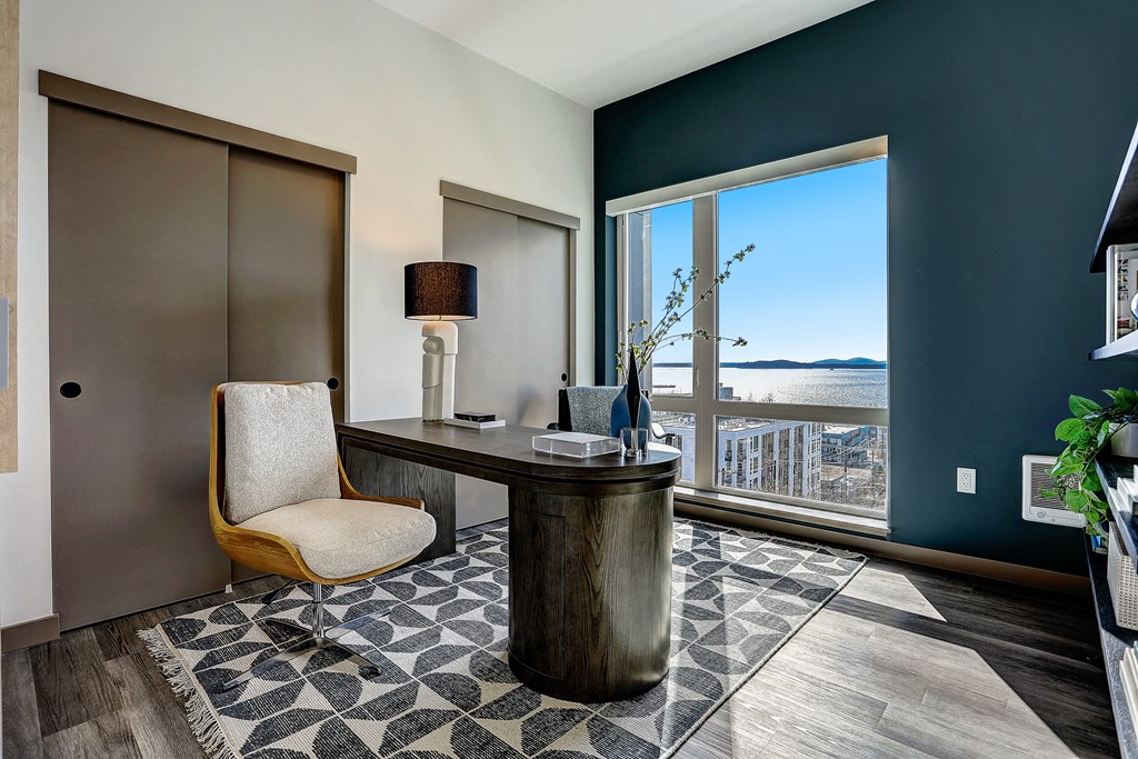 a home office with a large window and a desk with a chair