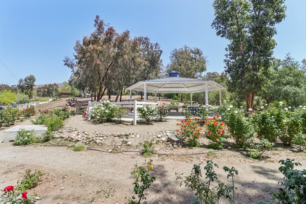 A garden with a gazebo surrounded by trees and flowers.