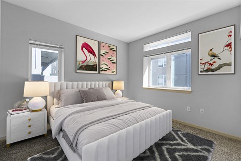A bedroom with a large bed, two nightstands, and two framed pictures on the wall.