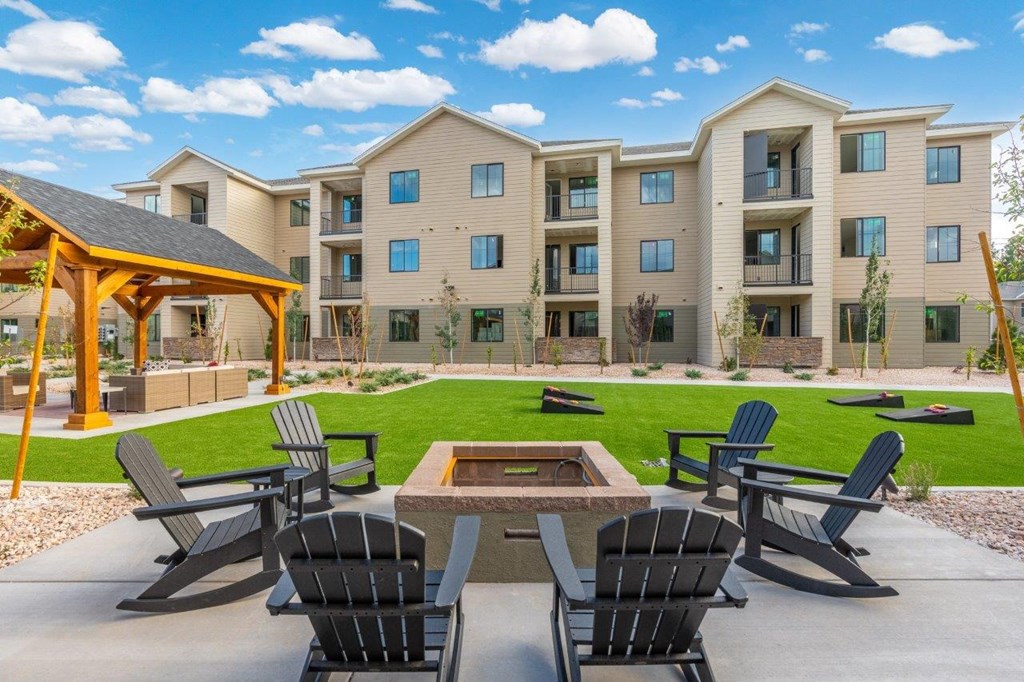 an outdoor patio with chairs and a fire pit in front of an apartment building
