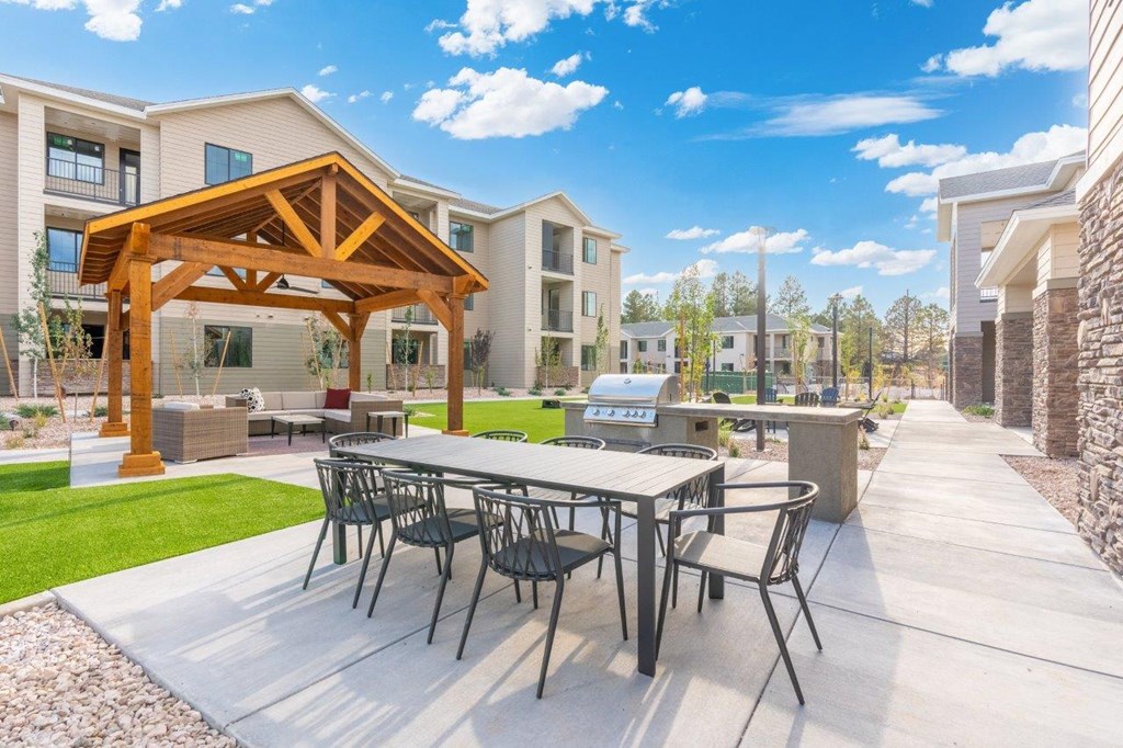 a patio with a table and chairs in front of a building