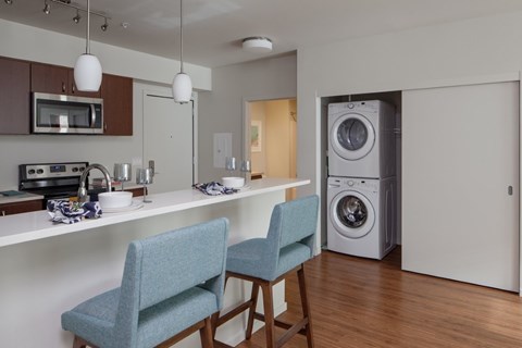 A modern kitchen with a blue chair and a washing machine.