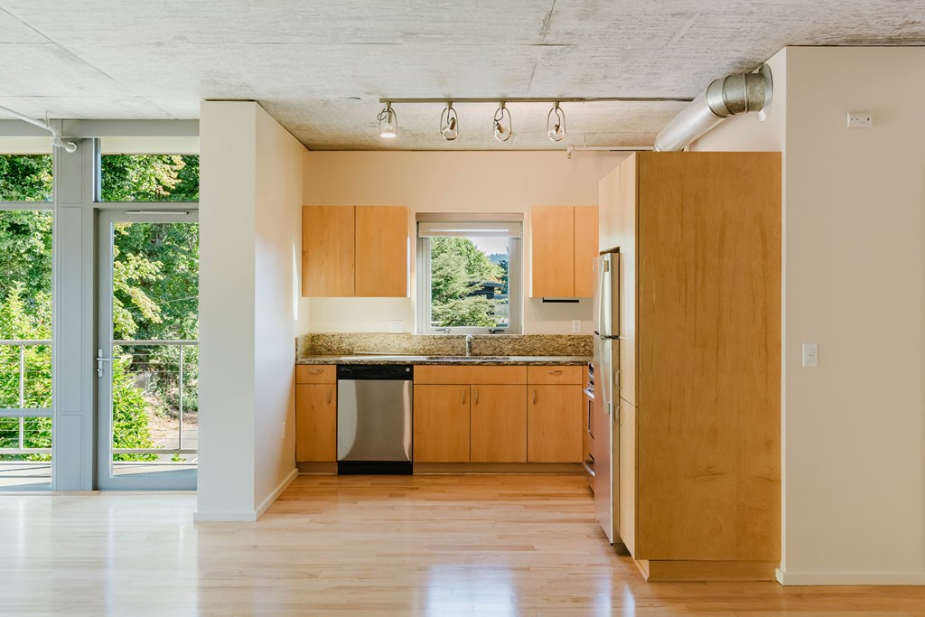 A kitchen with wooden cabinets and a window overlooking a green area.