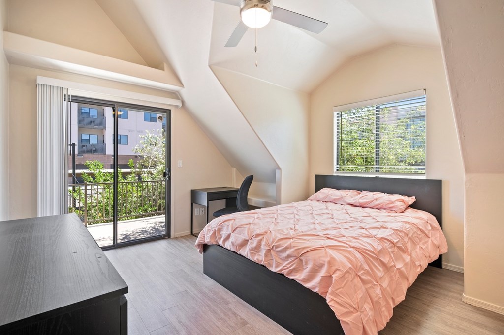 A bedroom with a bed, a chair, and a ceiling fan.