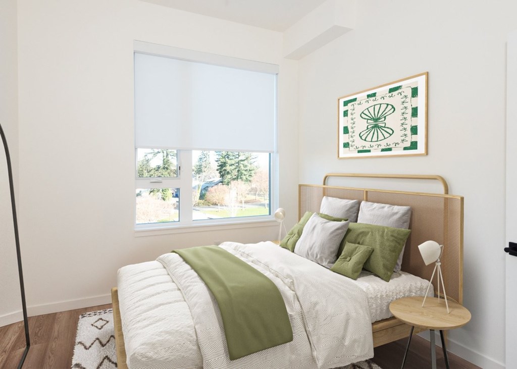 Arts Plaza Gresham Oregon Apartments A bedroom with a large bed and a green throw pillow.