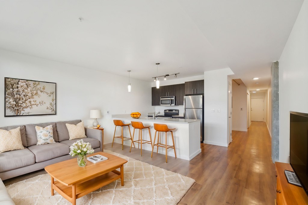 A living room with a grey couch, a wooden coffee table, and a painting on the wall.