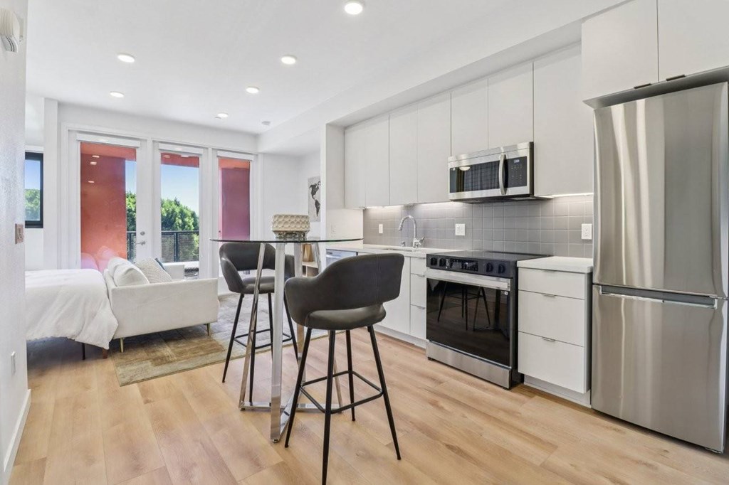 A modern kitchen with white cabinets and a wooden floor.