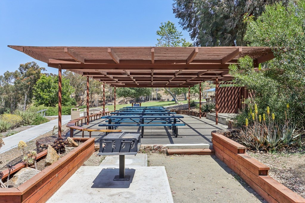 A wooden pergola with a table and chairs underneath it.