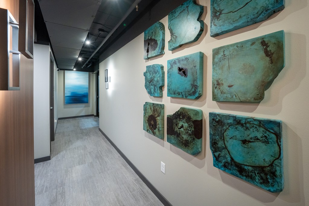 A hallway with a wall of artwork on the wall.