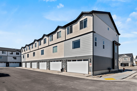 A modern two-story building with a garage door is situated in a parking lot.