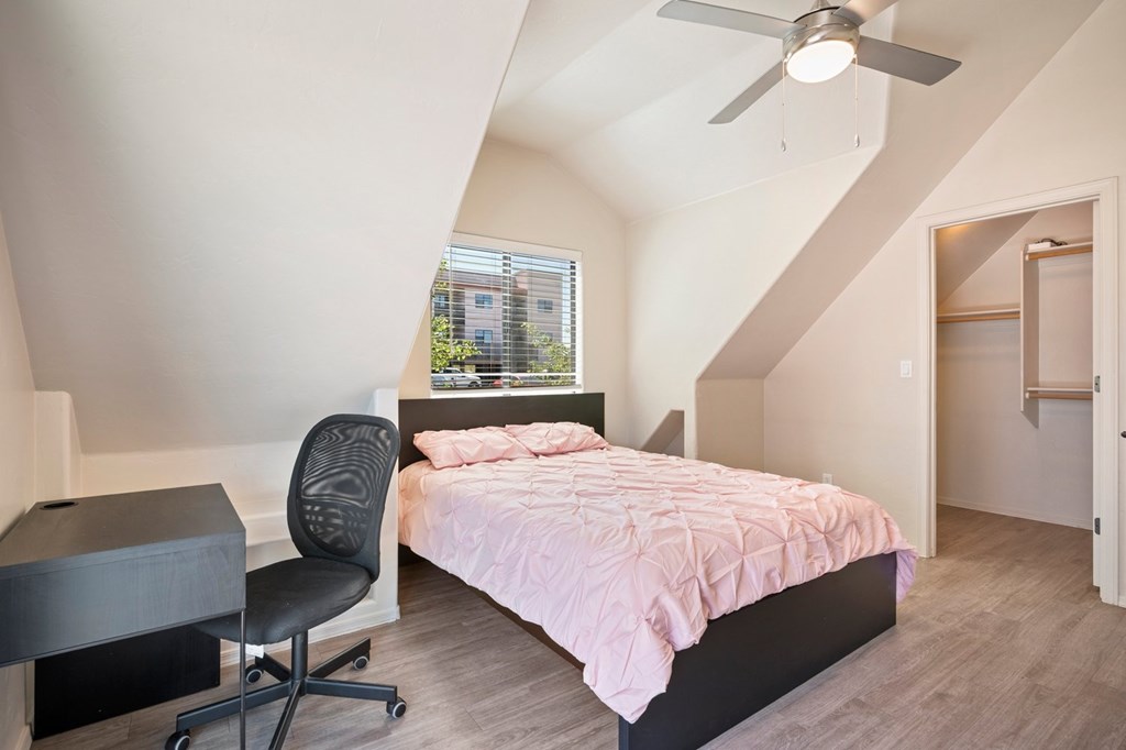 A bedroom with a bed, chair, and desk.