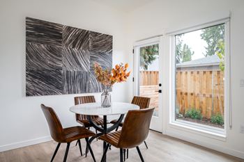 A dining room with a white table and chairs and a large abstract painting on the wall.