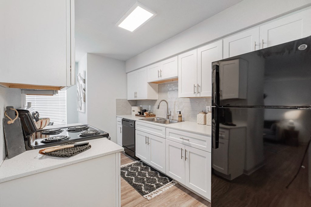 a kitchen with white cabinets and a black refrigerator