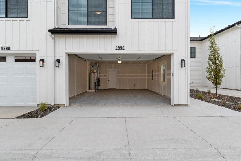 A white garage door is open to reveal a spacious garage.