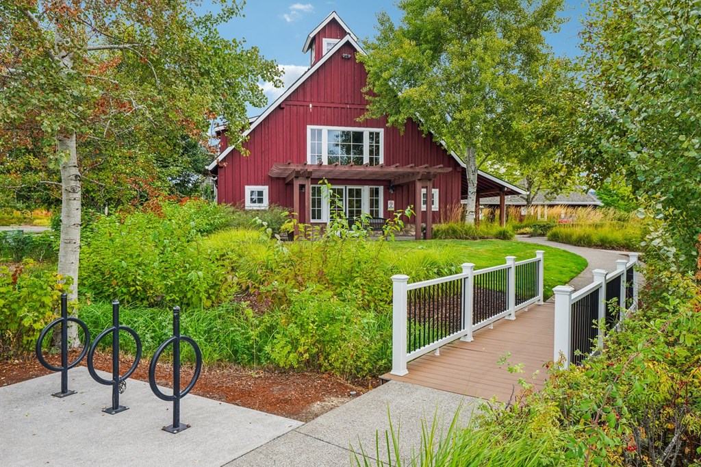 A red barn with a white fence and a walkway in front.