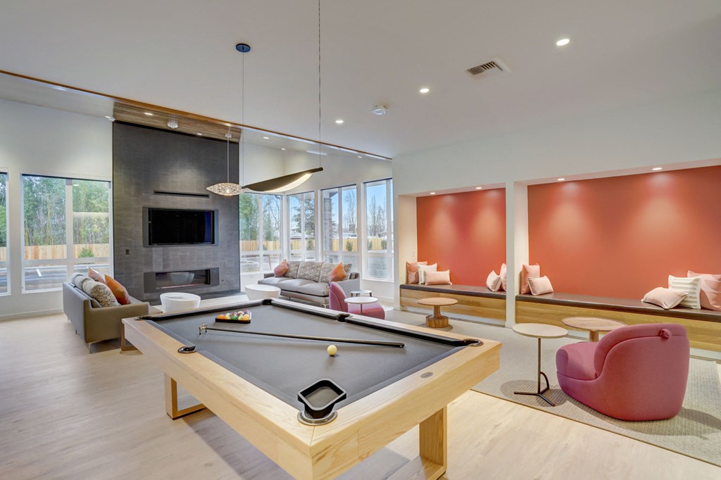 a pool table in the center of a living room with couches and a fireplace