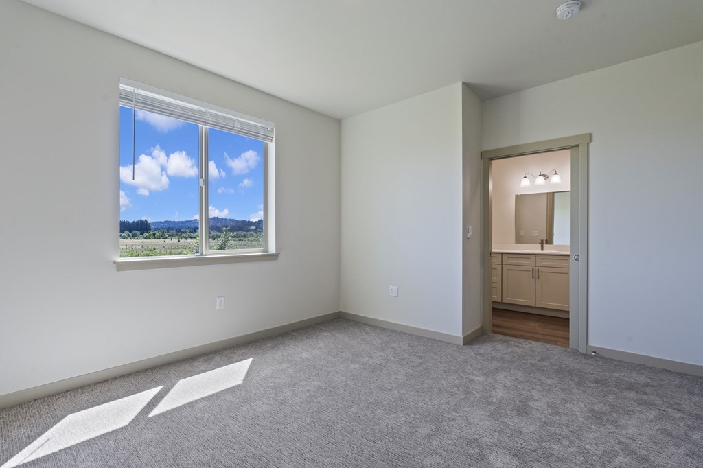 A room with a large window and a carpeted floor.