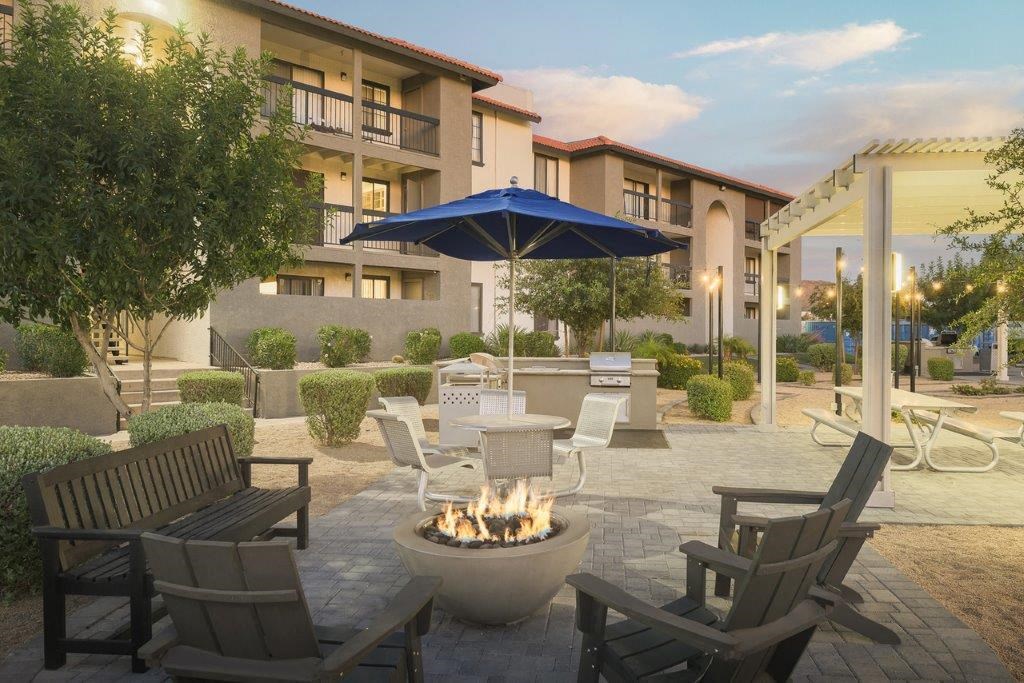 a patio with chairs and a fire pit