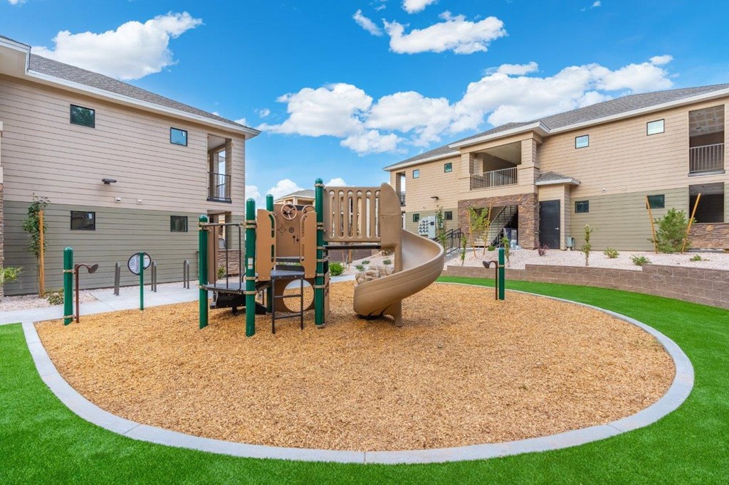 a playground with a slide in the middle of an apartment complex