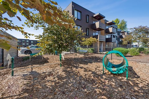 A playground with a green swing set in front of a modern building.