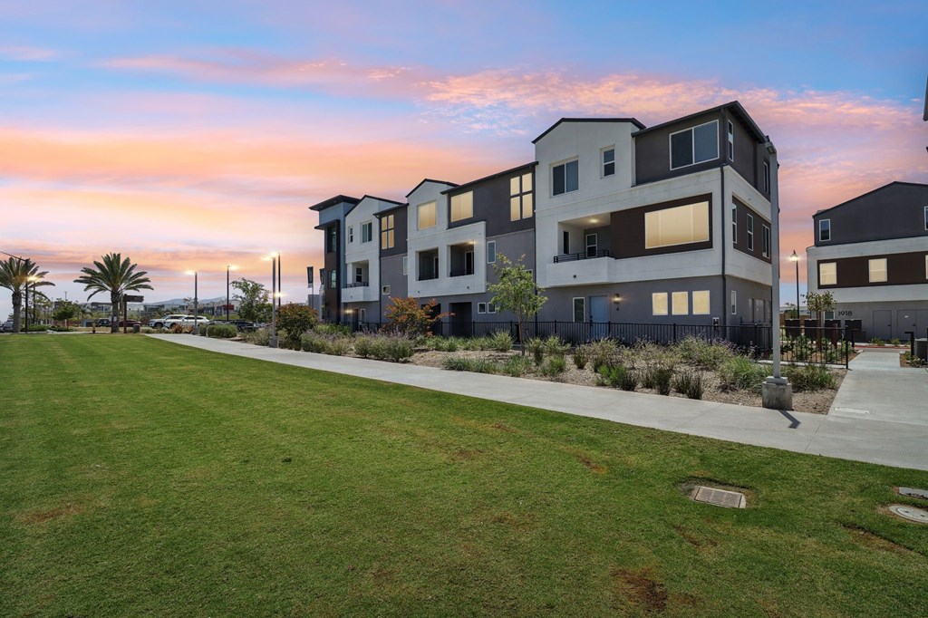 A modern apartment complex with a well-maintained lawn in front.