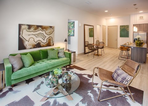 A living room with a green couch and a glass coffee table.