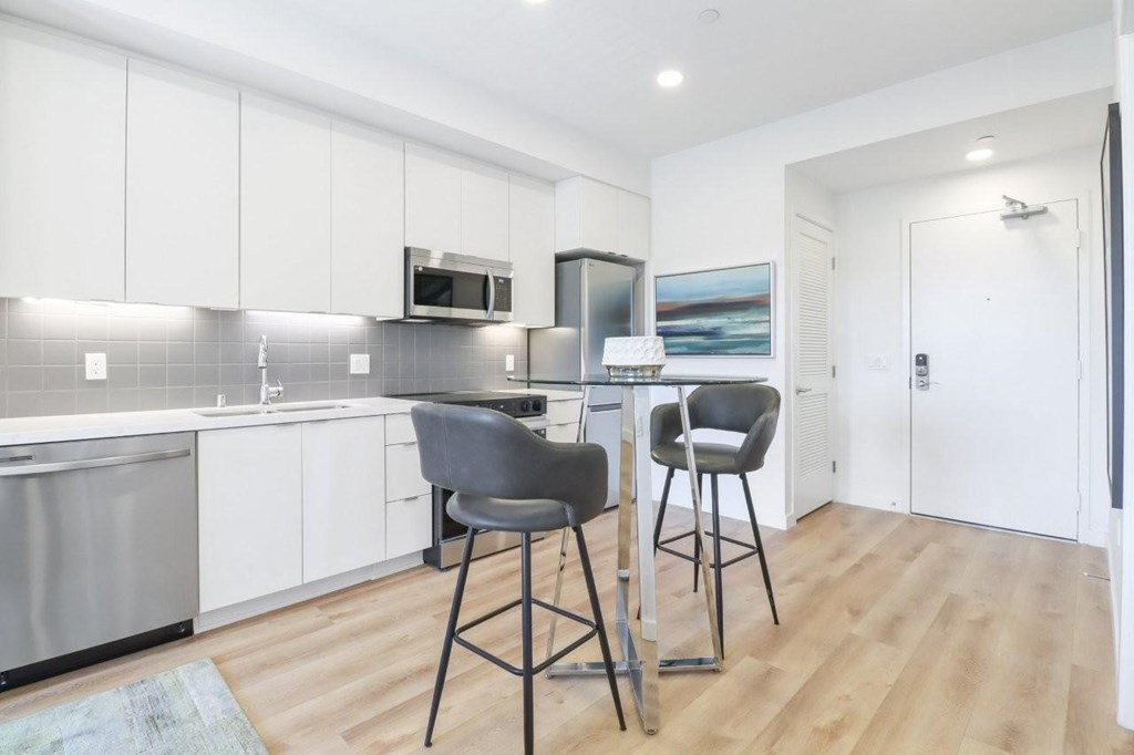 A kitchen with white cabinets and a grey counter top.
