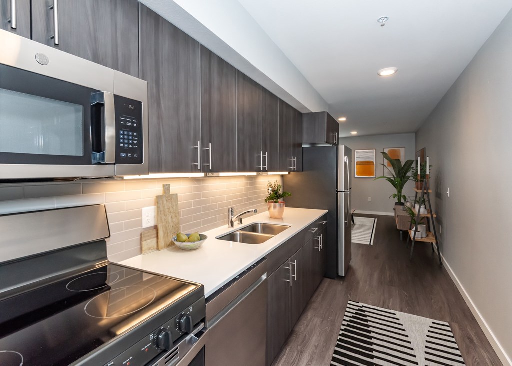 A modern kitchen with dark wood cabinets and stainless steel appliances.