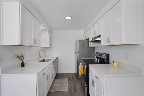 A kitchen with white cabinets and a black refrigerator.