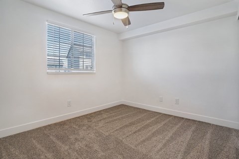 A room with a ceiling fan and carpeted floor.