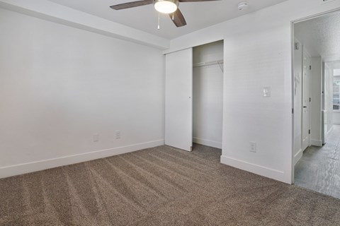 A room with a carpeted floor and a ceiling fan.