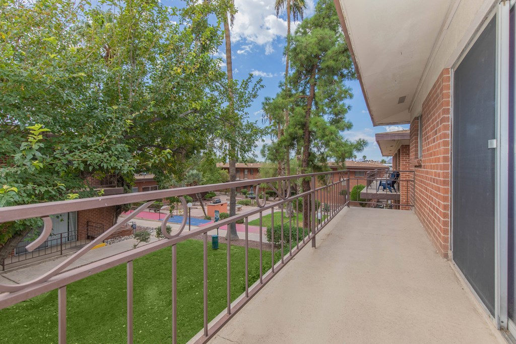 A balcony with a metal railing and a concrete floor.