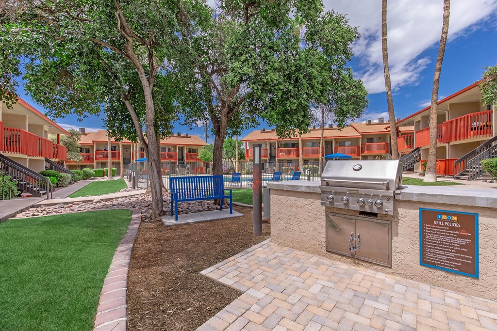 A BBQ grill is in the middle of a landscaped courtyard.